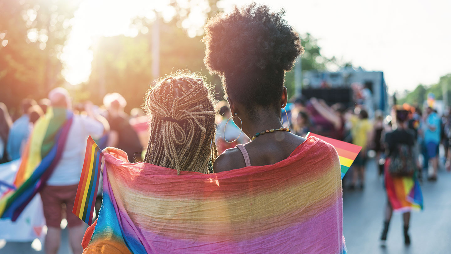 Couple wrapped in rainbow scarf at pride festival