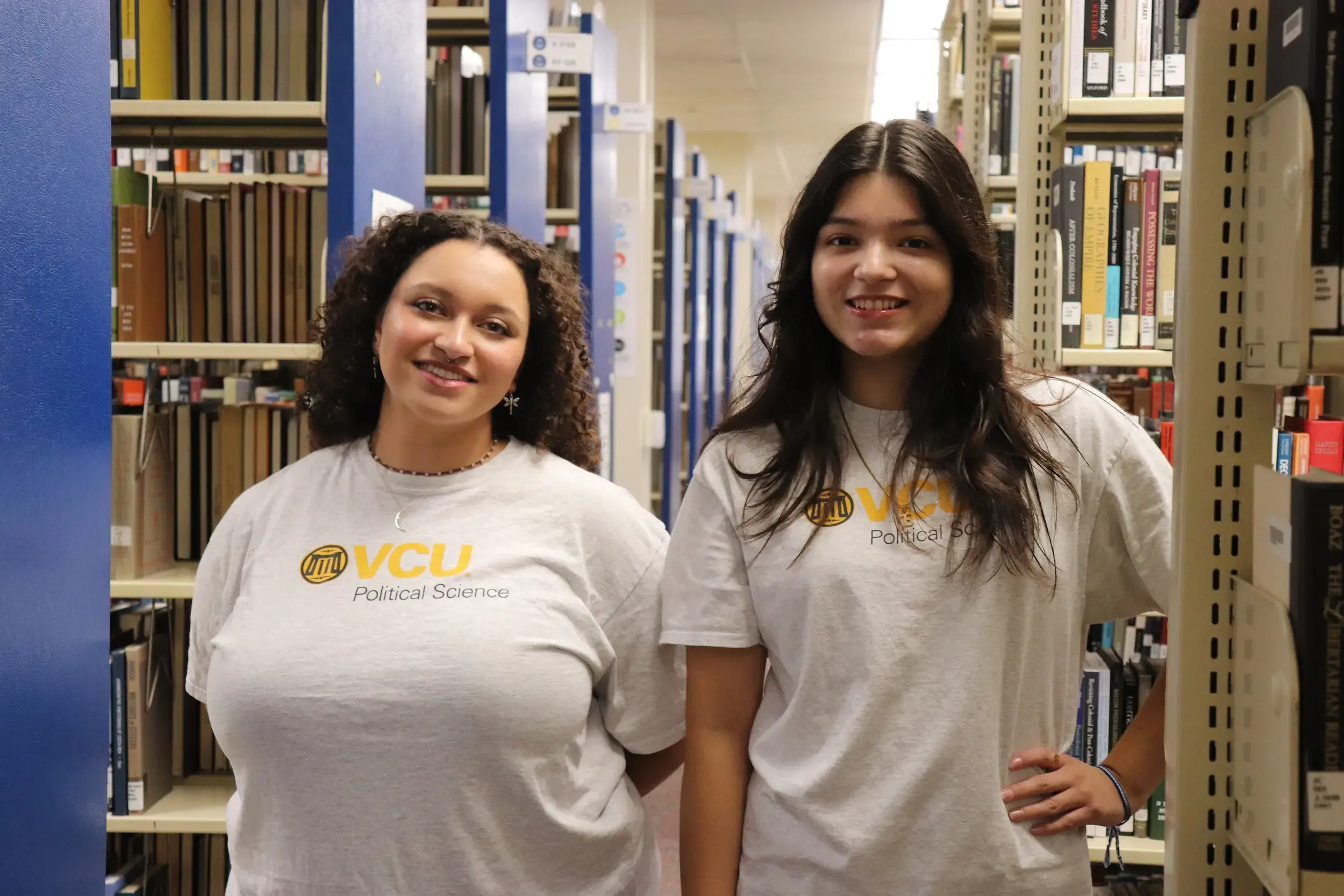 Emma Coffey and Liz Zepeda-Cantarero posing next to bookshelves