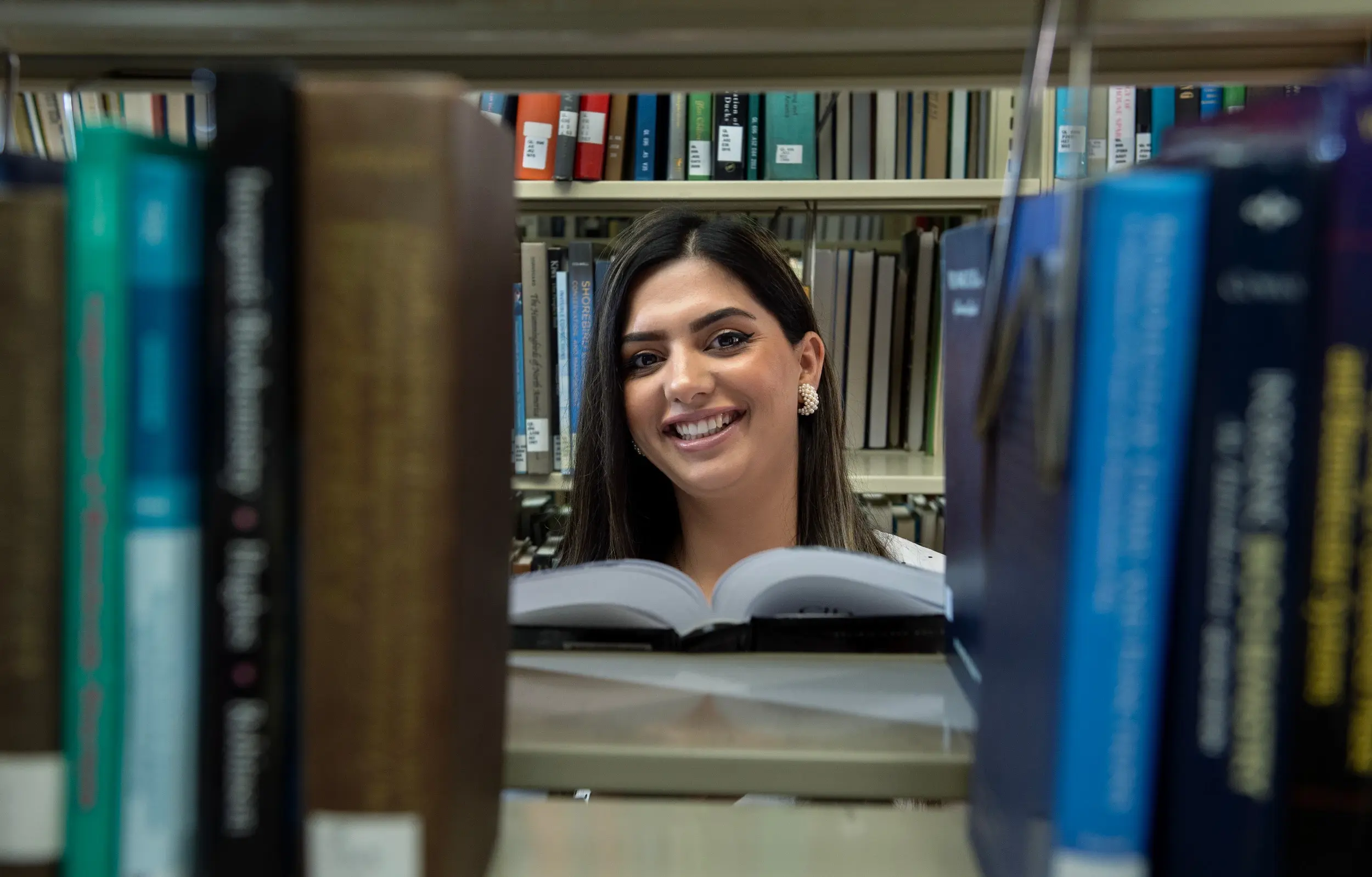 Sajia Afzali posing with books in foreground