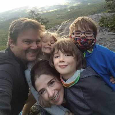 a family with a mom, dad, and three children pose happily in a mountainous settingone young girl.