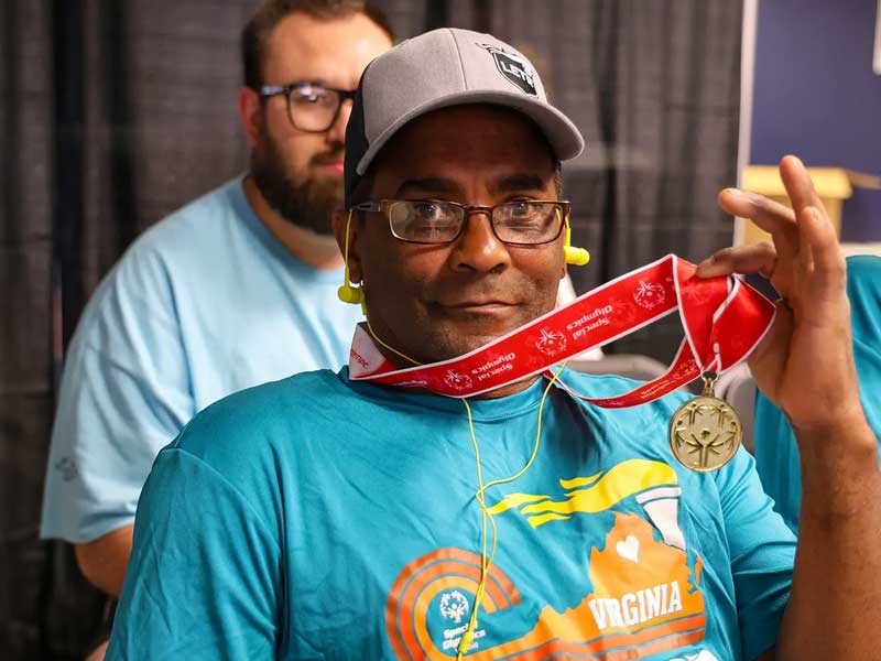 a person wearing a special olympics t-shirt and showing off a winner's medallion