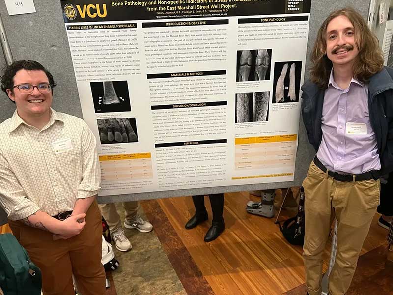 Finnegan Smith and Felix Arsenault stand in front of a research poster