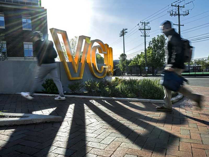 students walking past a v.c.u. sign on the v.c.u. campus